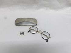 A vintage silver spectacle case with vintage spectacles