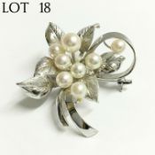 A cultured pearl brooch set with eight pearls in silver fashioned as a flower spray