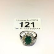 An 18ct oval diamond and emerald ring