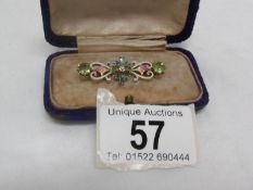 A yellow metal and enamel brooch set central diamond and 2 peridot