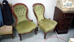 A pair of Edwardian mahogany spoon back nursing chairs with green deep buttoned upholstery