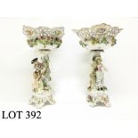 A pair of porcelain figures supporting flower encrusted bowls