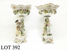 A pair of porcelain figures supporting flower encrusted bowls