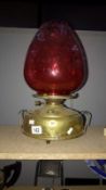 A brass and cranberry glass oil lamp