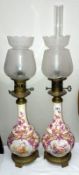 A pair of porcelain oil lamps with only one chimney and one shade a/f