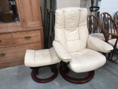 A cream leather revoling chair with foot stool