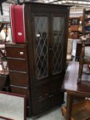 An oak corner cupboard with leaded glass door