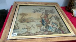 A framed and glazed 19th century tapestry of a shepherd, wife and baby with sheep, size including