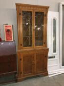 A light oak corner cupboard with leaded glass doors