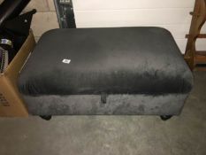 A grey fabric covered ottoman
