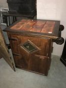 A oak cupboard with tile top