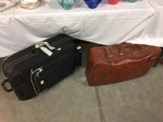 A large leather suitcase and a travel suitcase on wheels