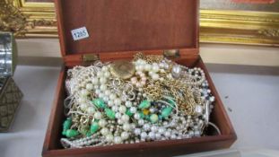 A large wooden box of costume jewellery