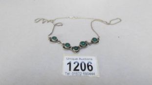 A silver necklace with green jadite stones