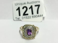 A yellow gold ring set with stones of suffragette colours,