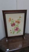 An oak framed embroidered fire screen