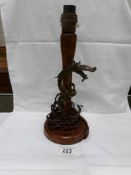 A vintage oak table lamp base with a bronze dragon entwined around the upright