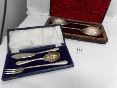 A cased pair of ornate serving spoons and a cased butterknife,