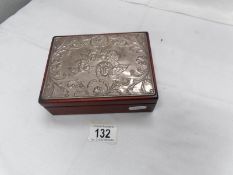 A silver topped cigarette box depicting cherubs