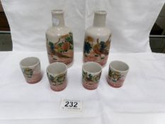 A Japanese sake set of 2 bottles and 4 cups all hand painted with golden pheasants and all signed