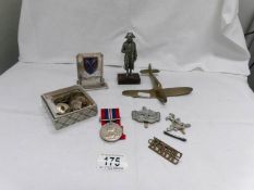 A collection of various military items including medal, buttons, badges, an antique brass figure,