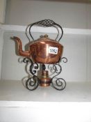 A copper kettle on wrought iron stand
