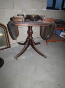 A mahogany effect centre pedestal drop leaf table