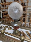 A brass oil lamp with etched shade