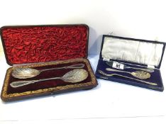 A cased pair of ornate serving spoons and a cased pickle fork, butter knife and spoon