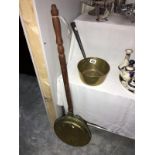 A brass warming pan and a brass saucepan