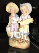 A pair of Edwardian bisque boy and girl figures