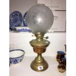 A brass oil lamp with etched shade (missing chimney)