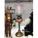 A Victorian brass column oil lamp with pink glass font