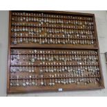 Large collection of souvenir teaspoons, many with enamel tops, in custom made wall display board