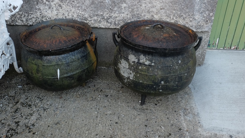 Similar pair of large Cast Iron Skillet Pots, with lids and carrying swing handles (damage to rim of