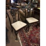 Pair of decorative mahogany chairs with ribbon carved splats in the Chippendale style.