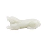 A WHITE JADE DOG 白玉臥犬 In a recumbent position with its head upturned, carved naturalistically to