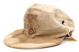 A Third Reich Afrika Korps peaked “ski cap”, faded to pale buff colour, the cockade and blue/grey