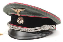 An SS peaked cap, with black velvet band, pink binding, metal insignia and silver bullion cords, the