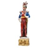 A painted porcelain figure of a Napoleonic Lancer officer, in full dress with sword, 11½” overall.