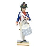 A Limoges painted porcelain figure of a Napoleonic French drummer, marching in full dress with