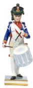 A Limoges painted porcelain figure of a Napoleonic French drummer, marching in full dress with