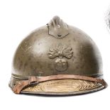 A World War I French Veteran’s Adrian steel helmet, with grenade badge to the front, painted olive