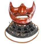 A Japanese red lacquered lower face guard, Mempo, with hooked nose and chin, from which hangs a