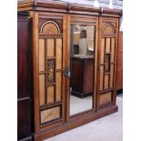 A Victorian Aesthetic Movement walnut ash and ebonised triple wardrobe with marquetry panels,