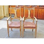 A pair of Edwardian Art Nouveau style oak armchairs. W55cm D61cm H116cm.