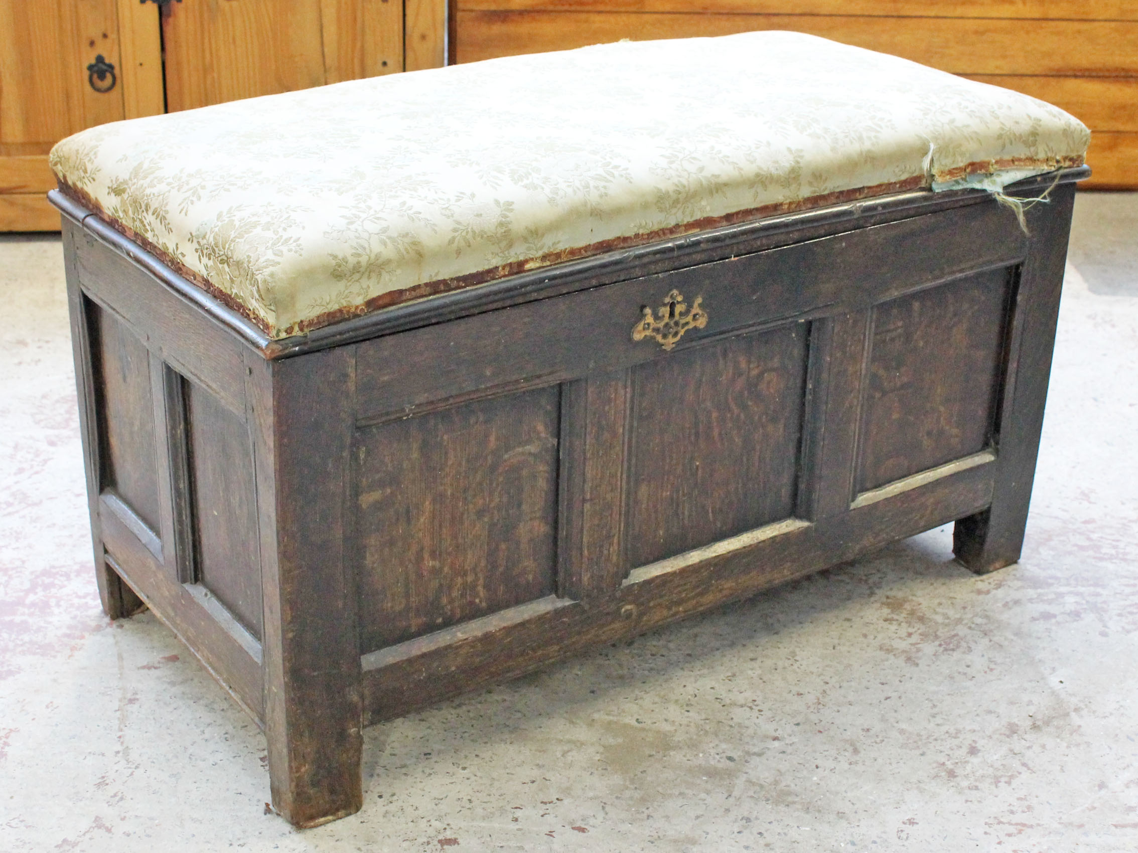 A 17th/18th Century oak coffer with later upholstered top. L100cm D50cm H56cm.