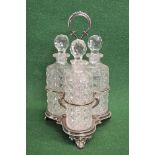 Silver plated three bottle decanter tantalus having hoop handle and standing on three scrolled feet,