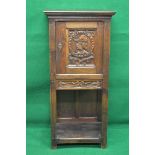 Oak carved cupboard on stand having single carved panelled door opening to reveal single fixed