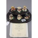 Set of six tiny Royal Doulton Kings & Queens of the realm character jugs on wooden display stand -